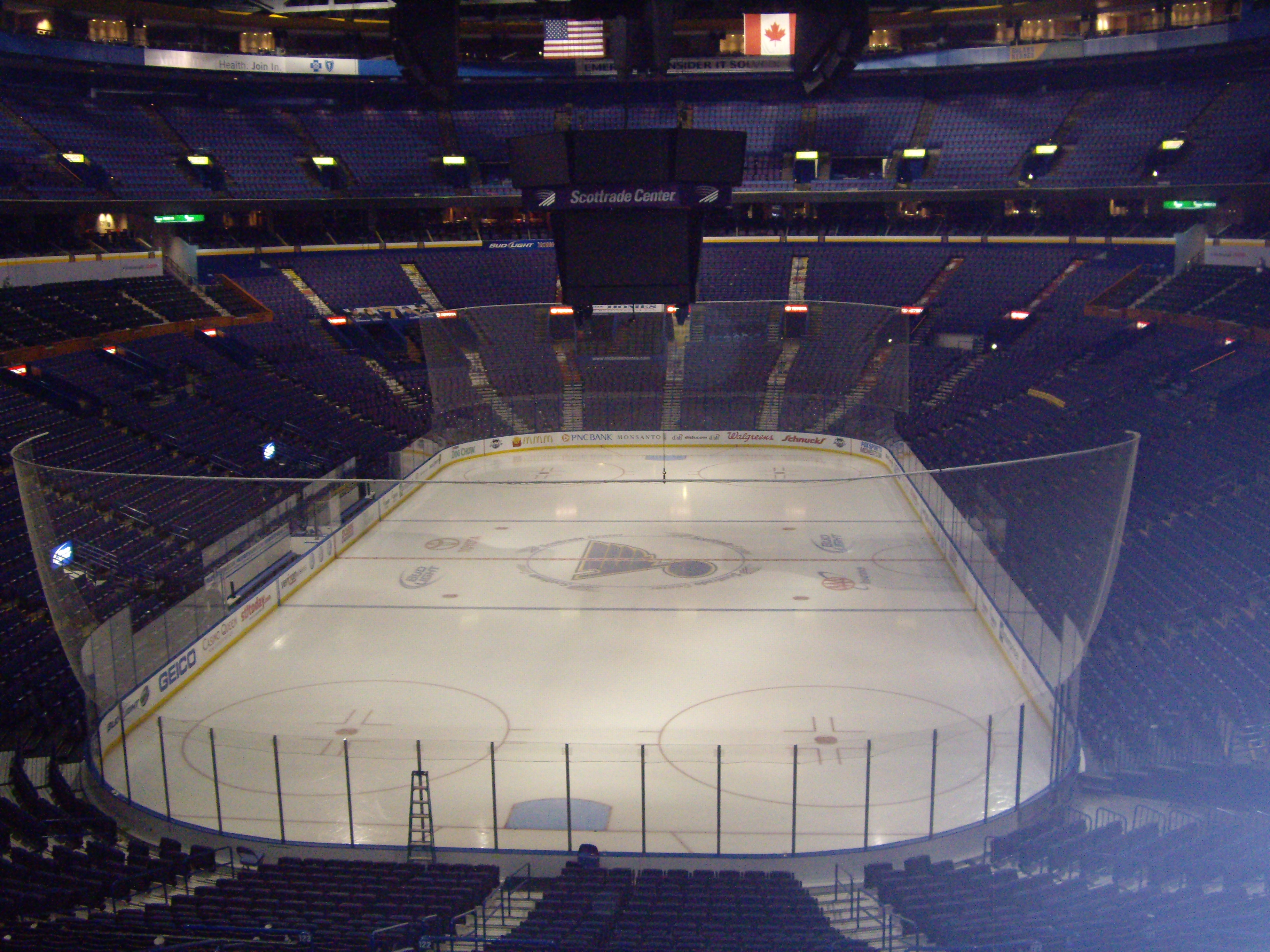 An empty NHL arena with the ice rink and centre-hung scoreboard visible.