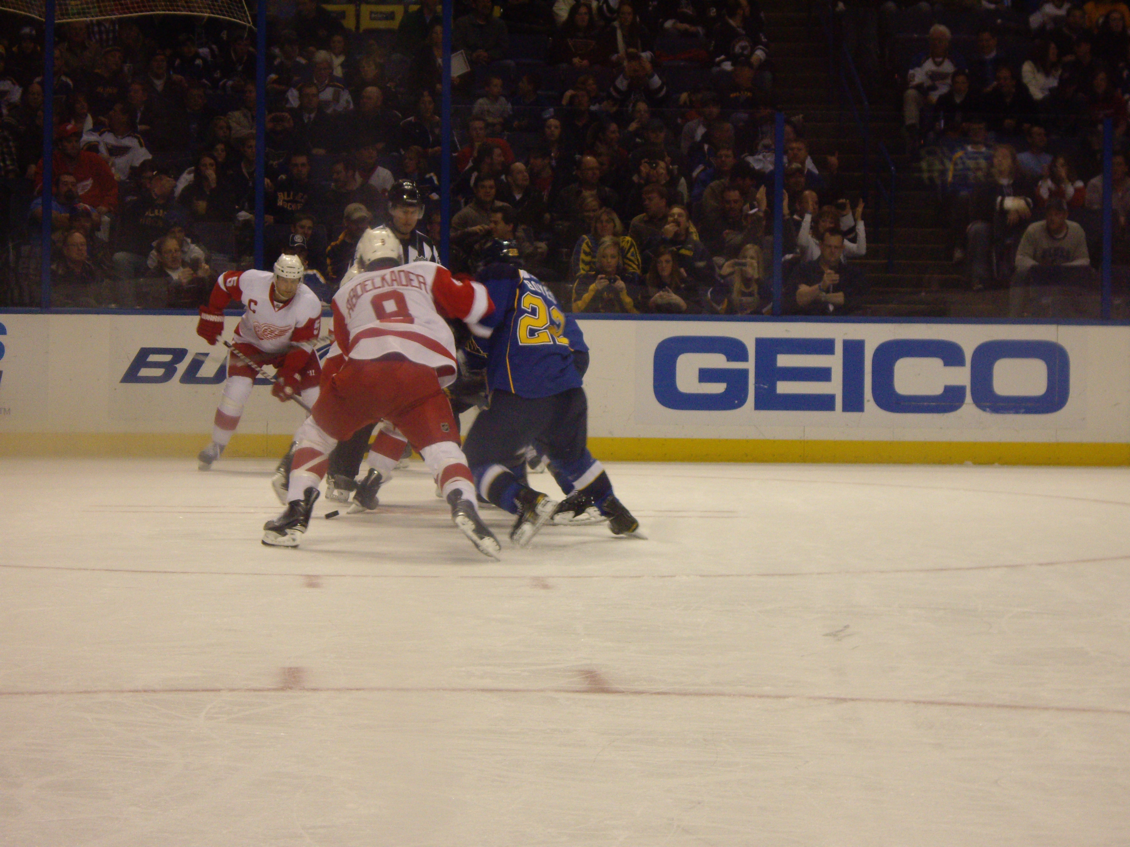 Detroit Red Wings and St. Louis Blues players competing during an NHL game.